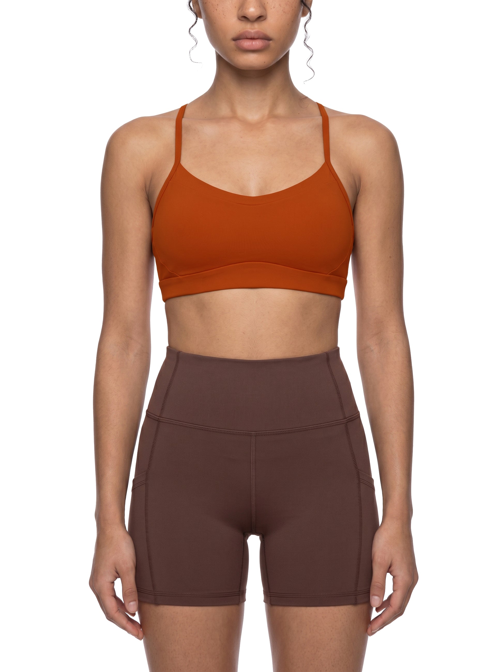 Person wearing a orange sports bra and shorts on a white background