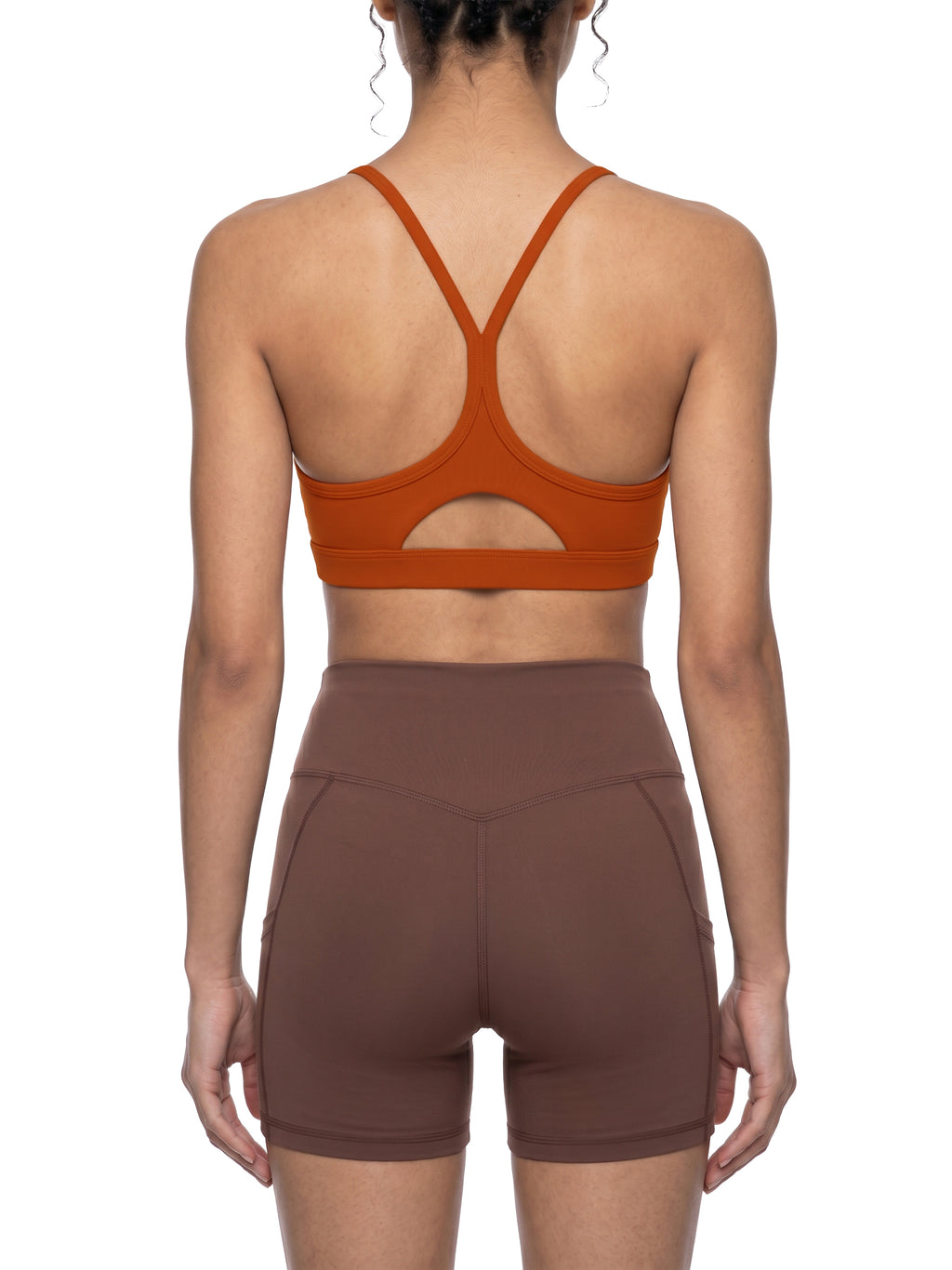 Person wearing a brown sports bra and shorts on a white background