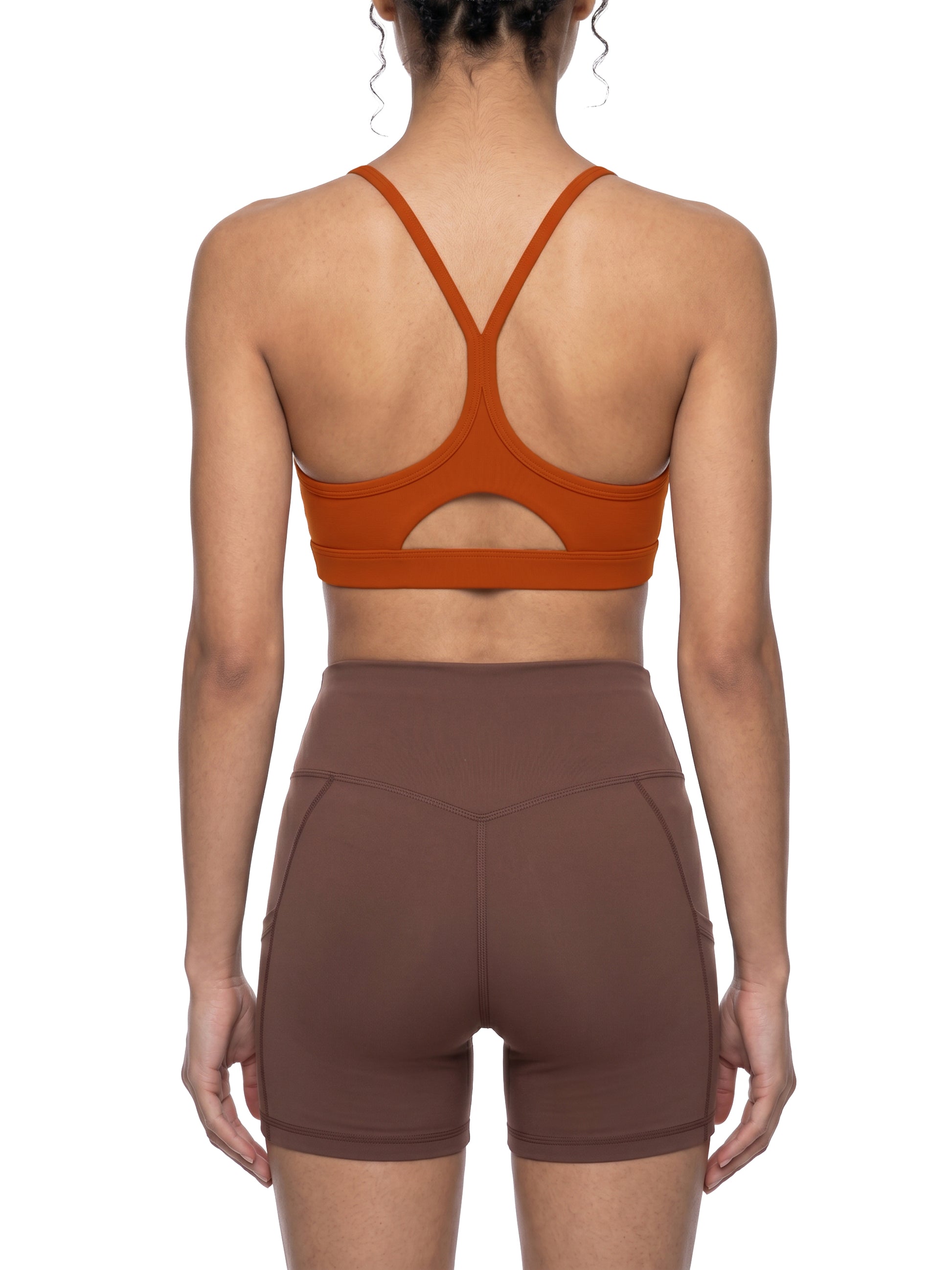 Person wearing a brown sports bra and shorts on a white background