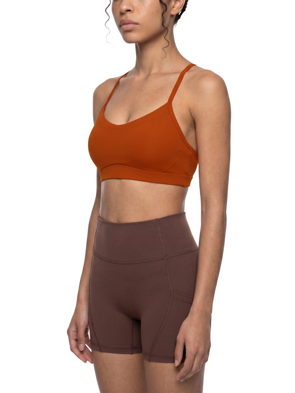 Woman wearing a brown sports bra and shorts on a white background