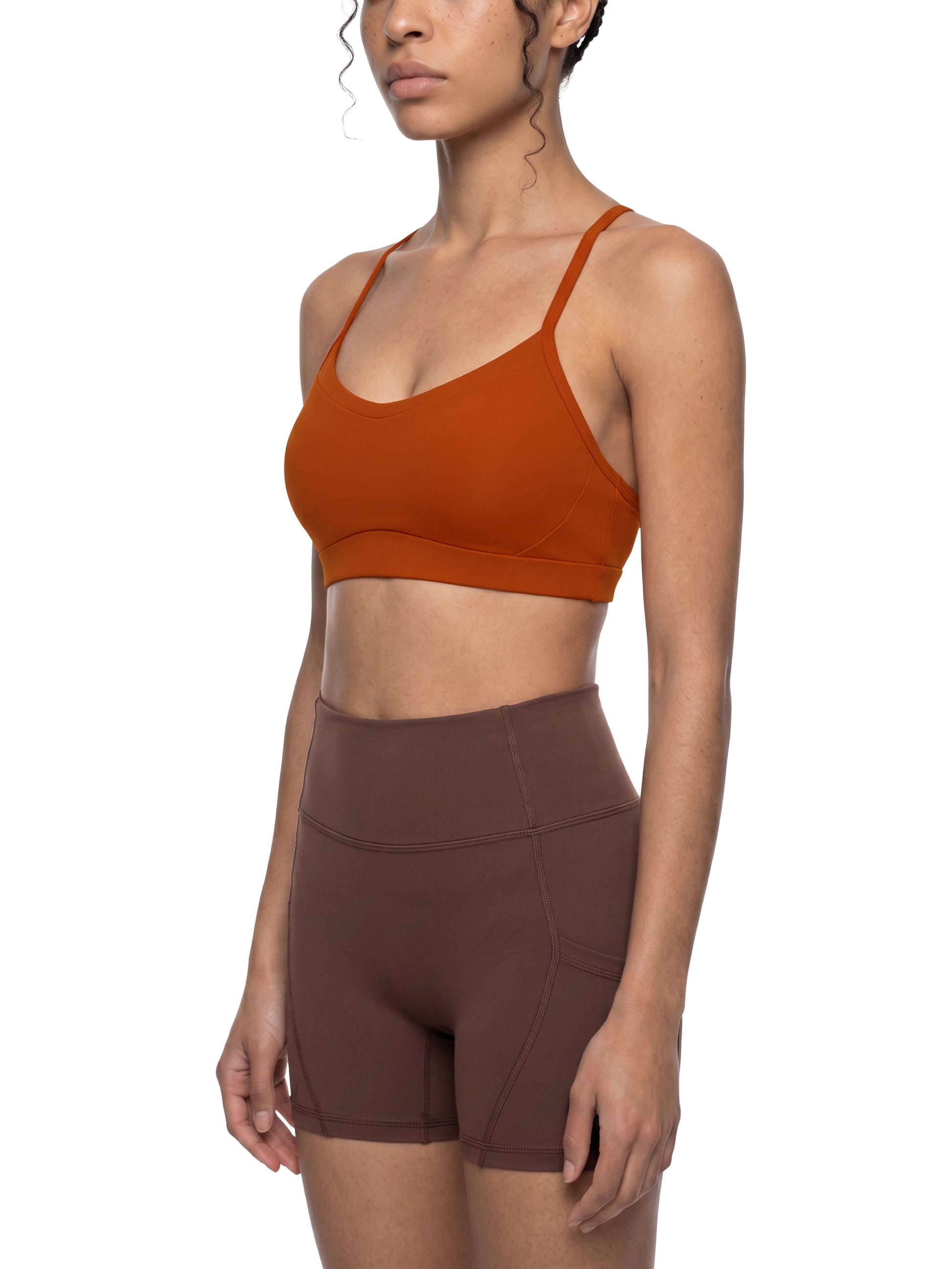 Woman wearing a brown sports bra and shorts on a white background
