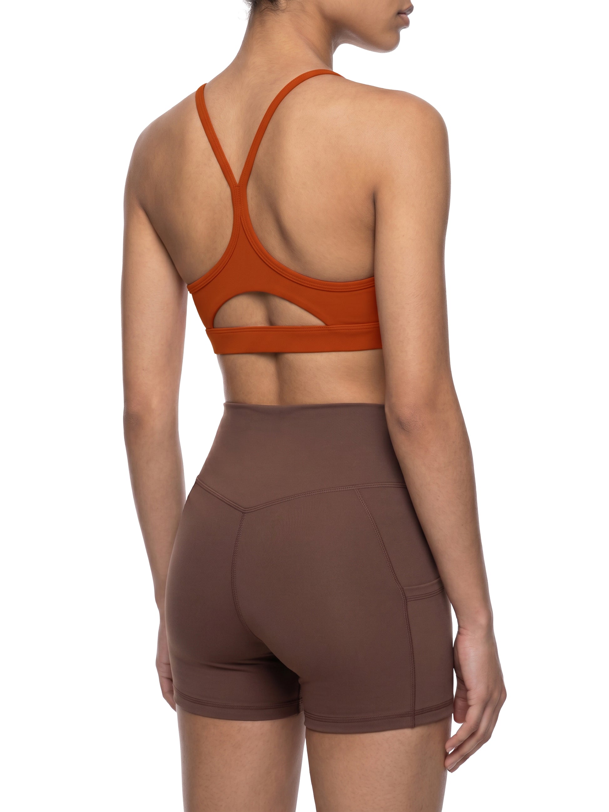 Person wearing a brown sports bra and shorts set on a white background